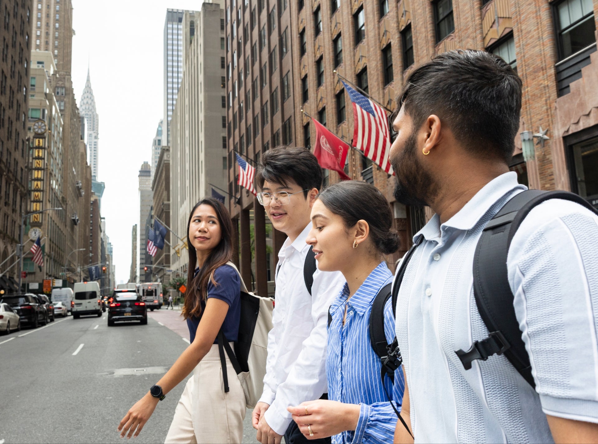 Four Baker Program students cross the street in NYC with the 570 Lex building and a Cornell University flag visible in the background.