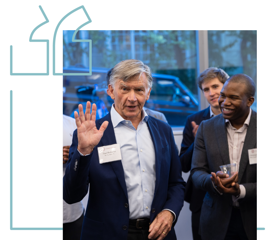 Paul Rubacha speaks with his hands while a group of people clap in the background.