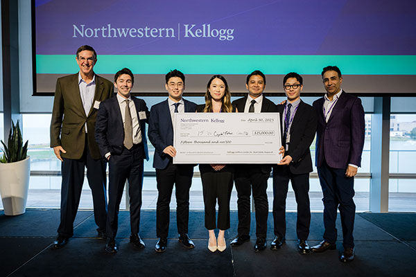 One older man standing next to 6 students in business attire holding novelty check for $15,000.