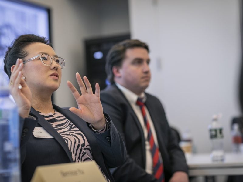 Two students in professional attire engaging in classroom lecture