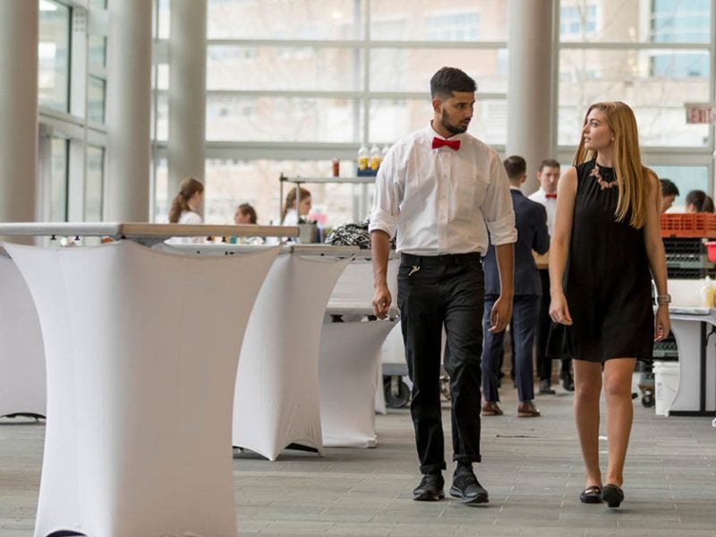 Two students walk through a ballroom as they prepare for an event.