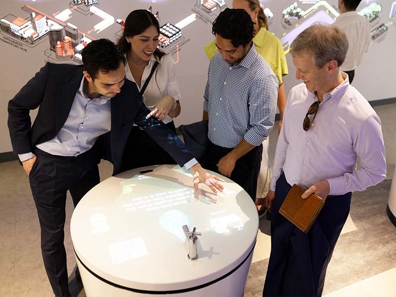 A group of four people (students and faculty) viewing a piece together at an exhibit.